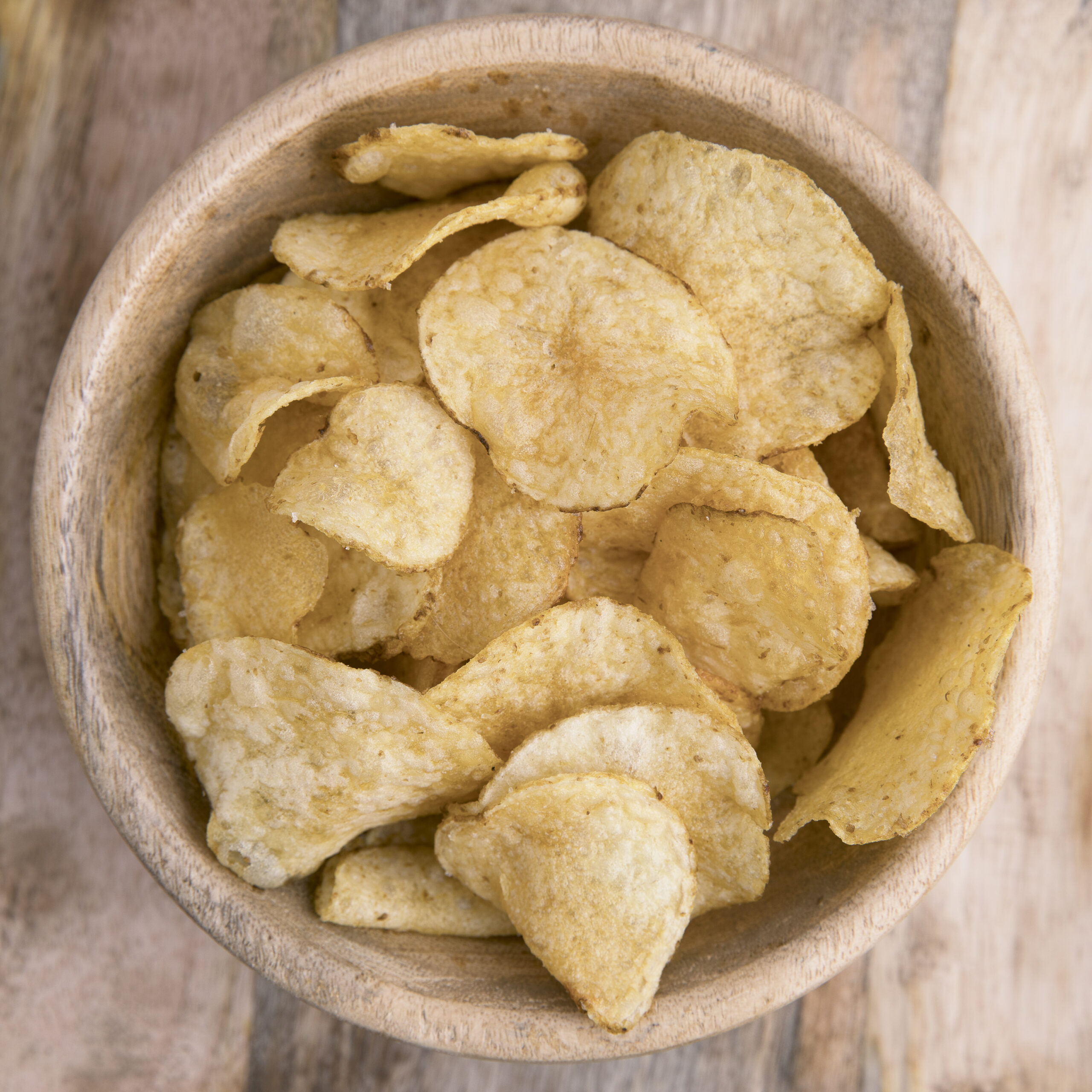 Wooden bowl filled with chips viewed from above.
