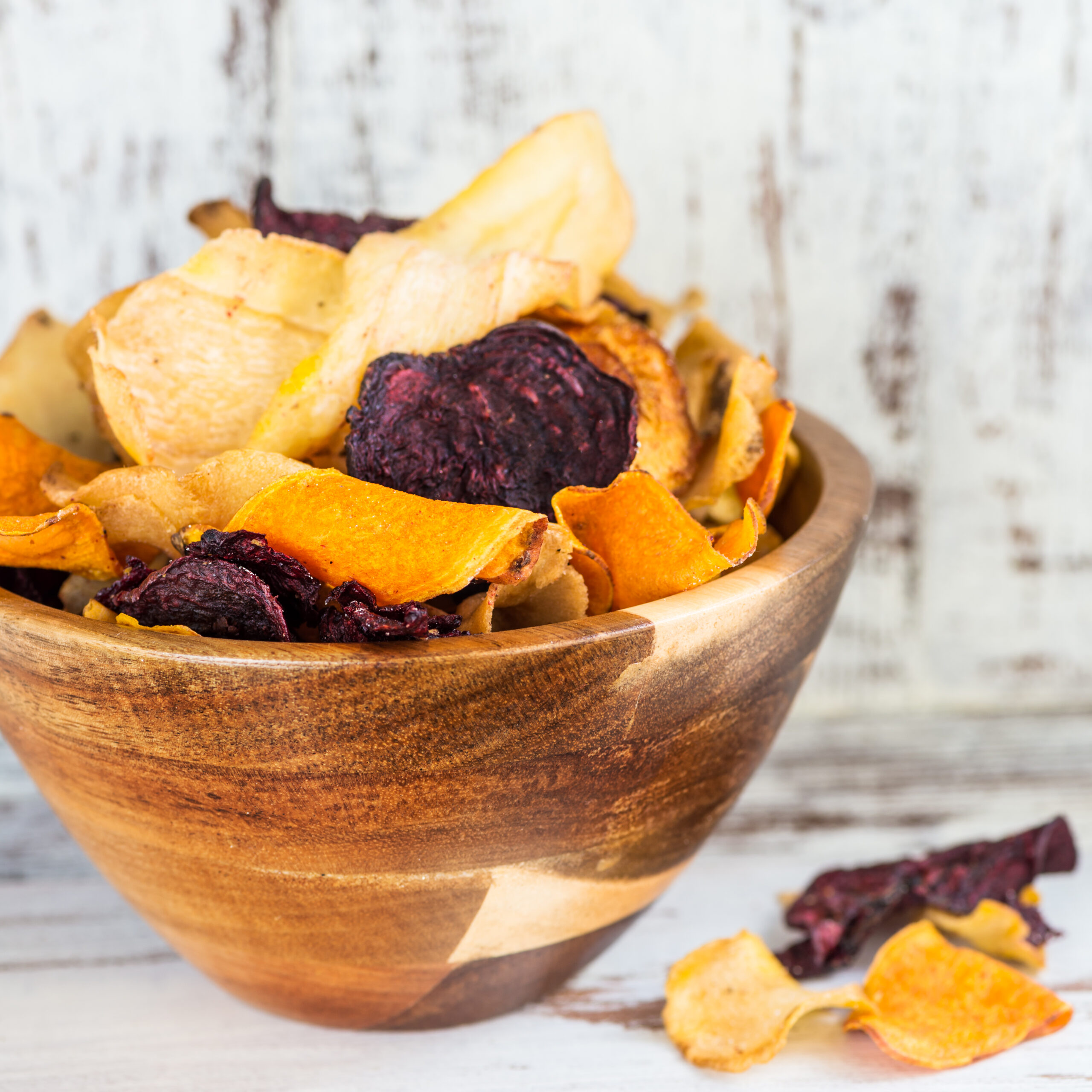Bowl of Healthy Snack from Vegetable Chips, such as Sweet Potato, Beetroot, Carrot, Parsnip on Light Wooden Background