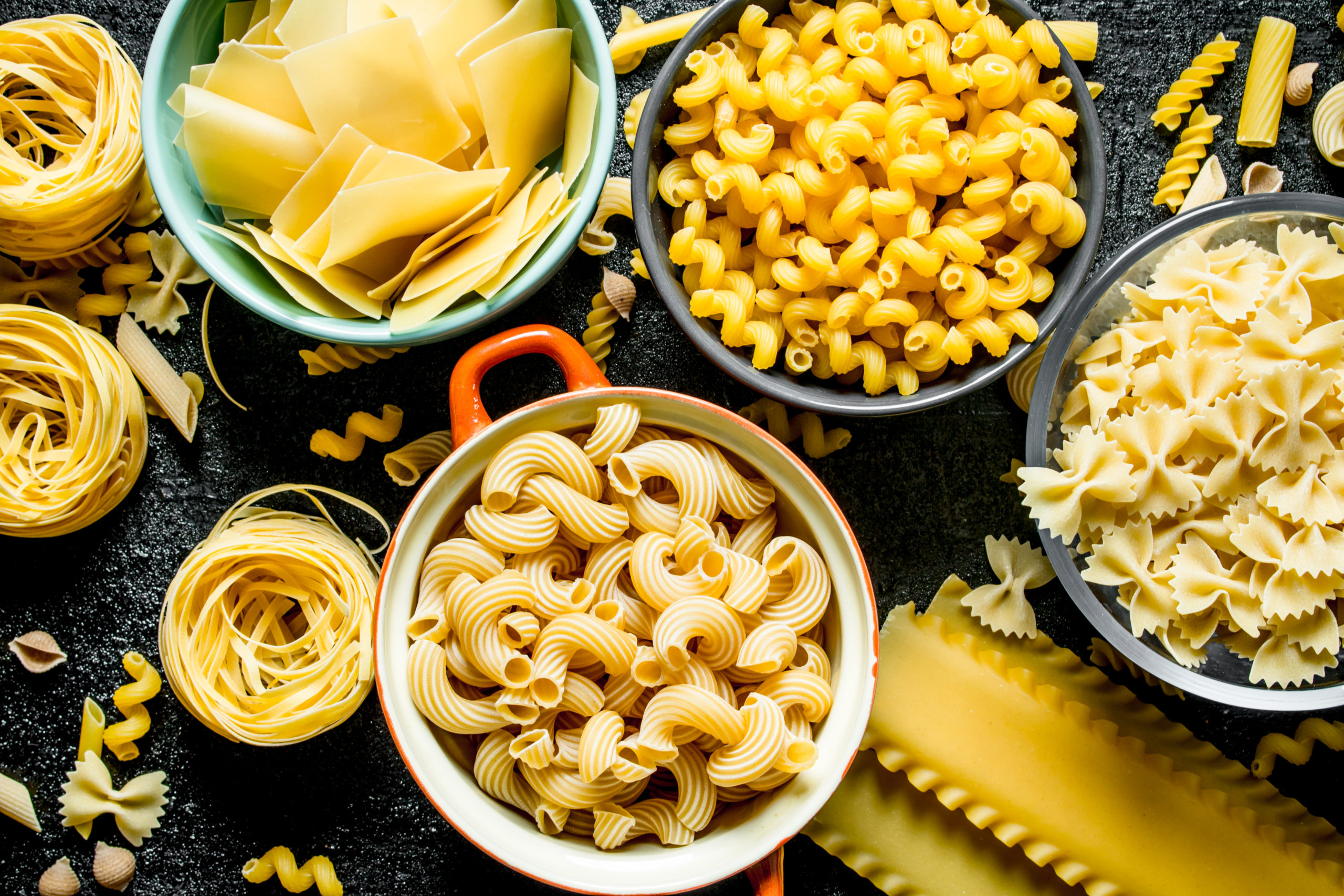 Pasta background. Different types of dry pasta in different bowls.