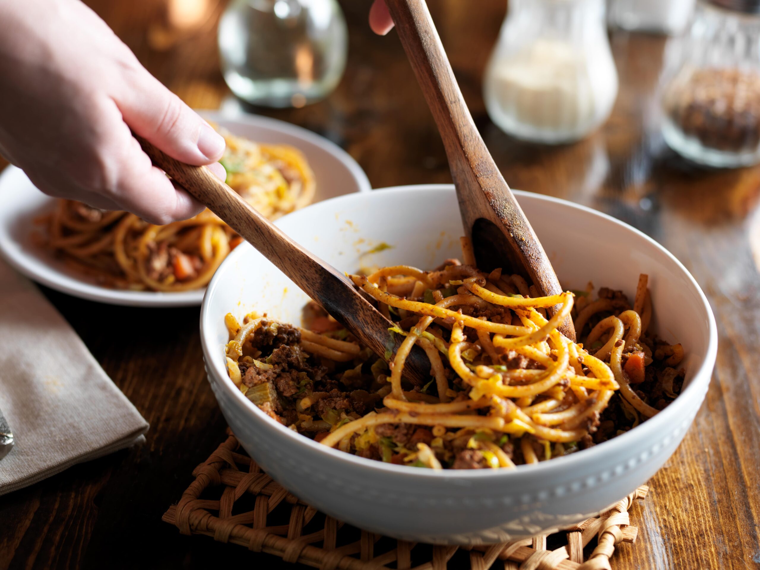 serving spaghetti with wooden spoons out of bowl cook at home